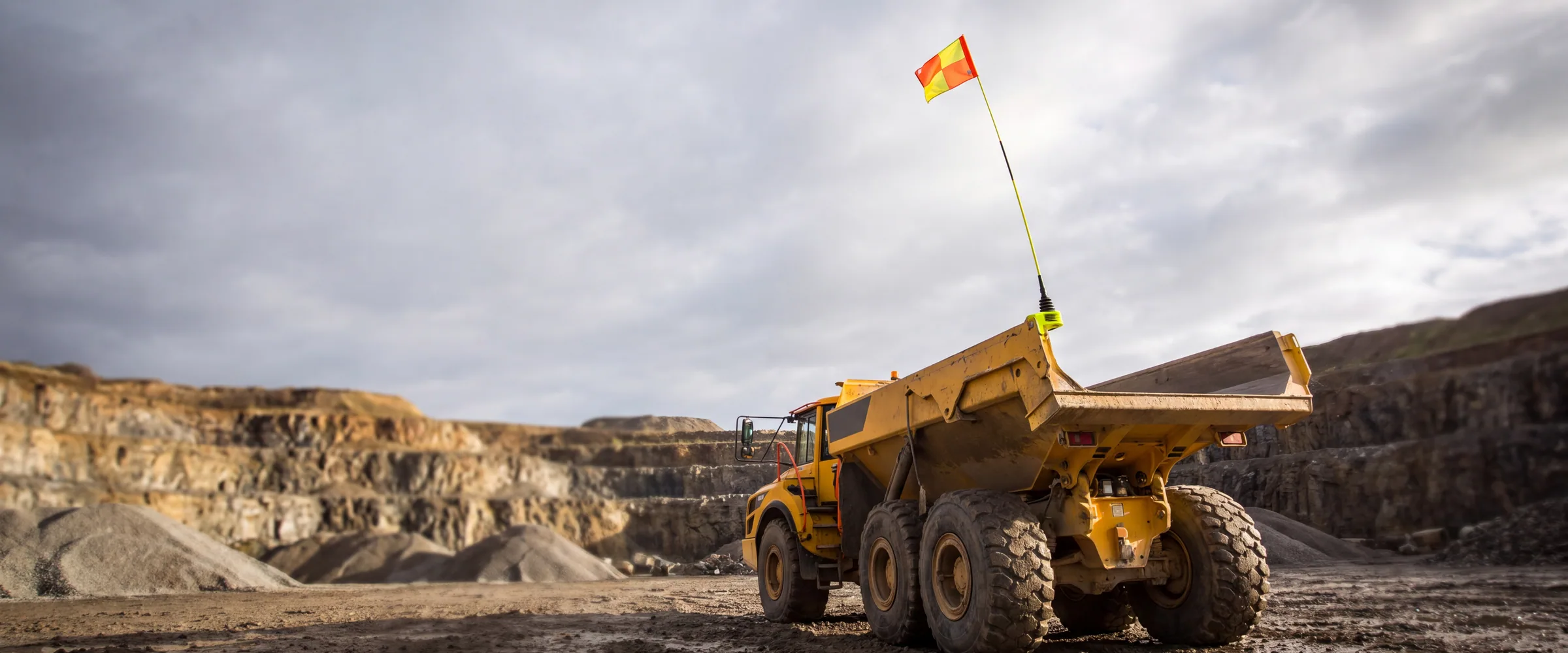 A buggy whip mast and safety flag fitted to a site dumper in a quarry